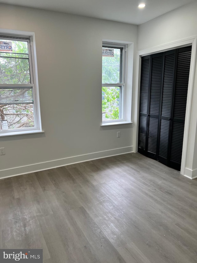 unfurnished bedroom featuring baseboards, recessed lighting, wood finished floors, and a closet