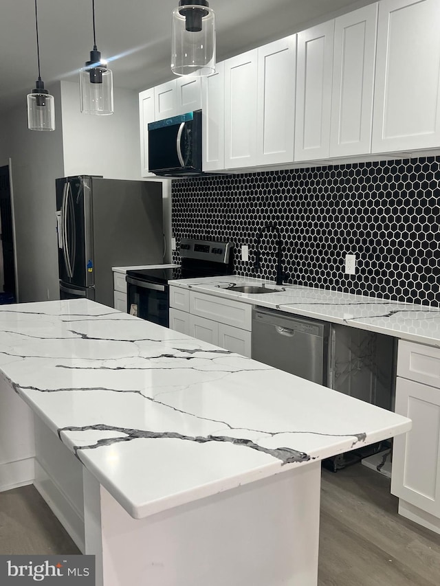 kitchen with decorative backsplash, wood finished floors, white cabinetry, decorative light fixtures, and stainless steel appliances