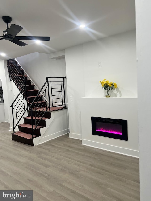 unfurnished living room with baseboards, wood finished floors, and stairway
