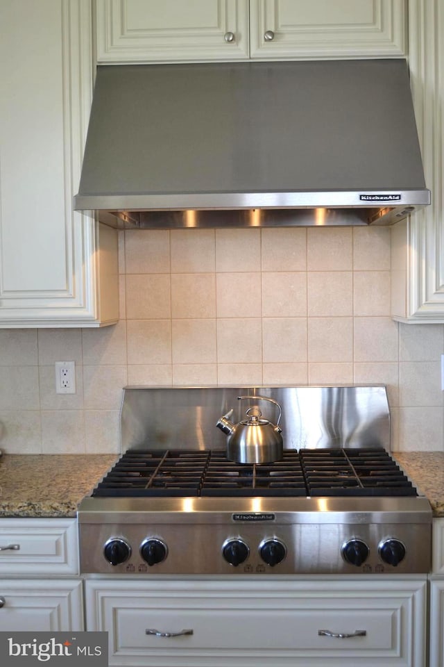 room details featuring backsplash, light stone countertops, stainless steel gas stovetop, and extractor fan