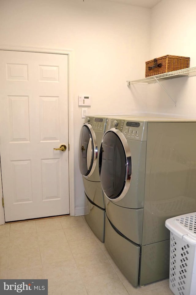 washroom with light tile patterned flooring, washing machine and clothes dryer, and laundry area