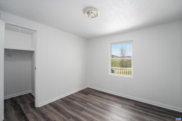 unfurnished bedroom with a textured ceiling and dark wood-type flooring