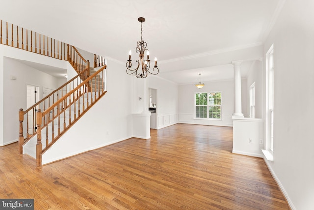 unfurnished living room with stairway, crown molding, wood finished floors, and a chandelier