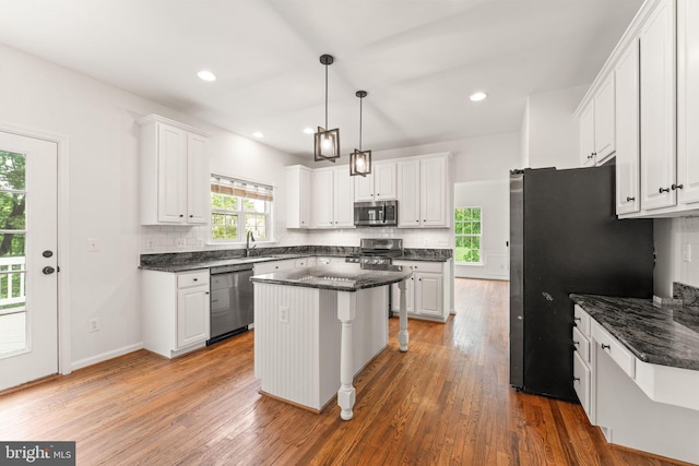 kitchen with appliances with stainless steel finishes, tasteful backsplash, white cabinets, a kitchen island, and recessed lighting
