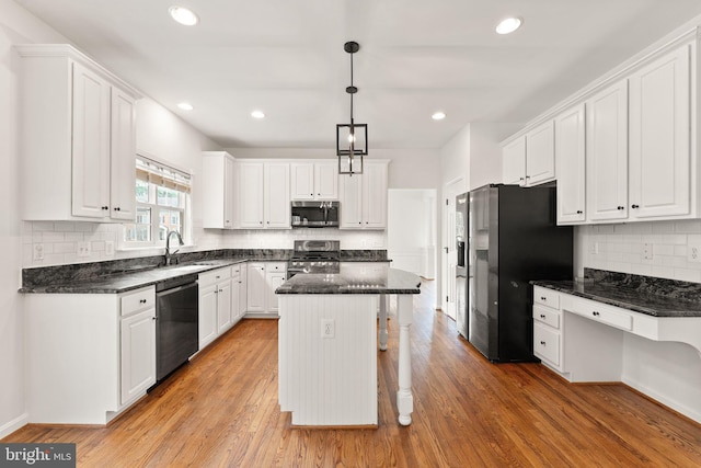kitchen with stainless steel appliances, white cabinetry, backsplash, a kitchen island, and light wood-style flooring
