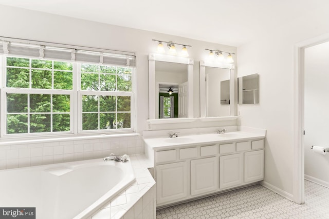 full bathroom featuring a bath, double vanity, ceiling fan, and baseboards