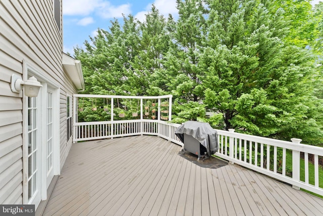 wooden terrace with area for grilling and view of scattered trees