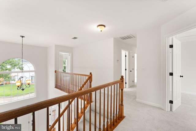 hallway with an upstairs landing, a chandelier, carpet floors, and baseboards