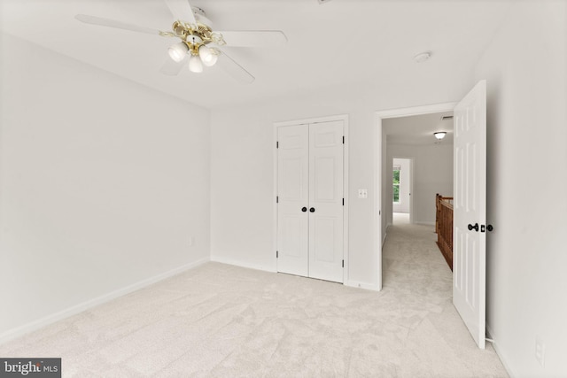 unfurnished bedroom with light carpet, a closet, and baseboards