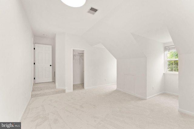 additional living space with lofted ceiling, light colored carpet, and baseboards