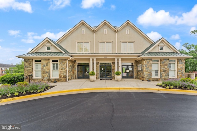 view of front facade featuring a standing seam roof, stone siding, and french doors