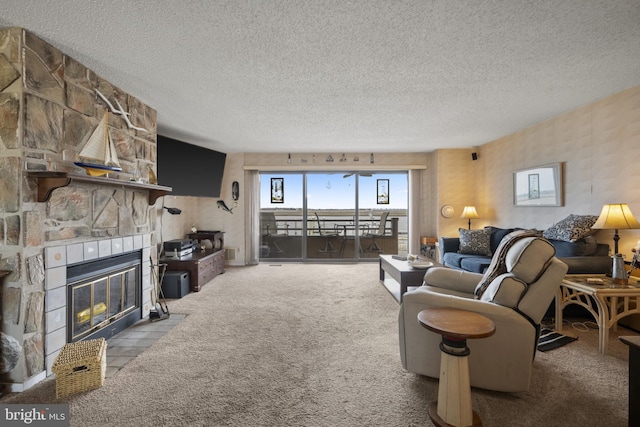 living area featuring carpet floors, a textured ceiling, and a stone fireplace