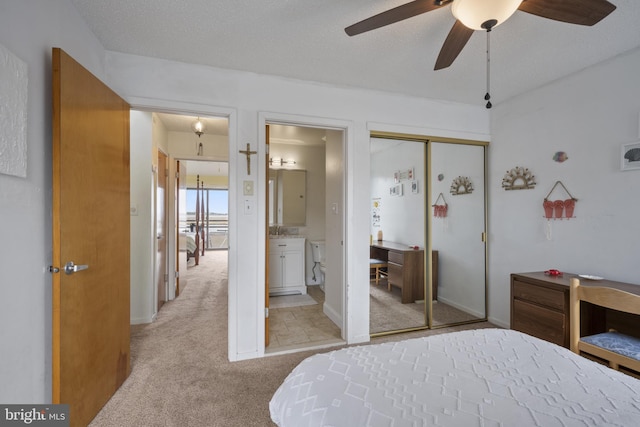 bedroom with ensuite bathroom, a closet, ceiling fan, light carpet, and baseboards