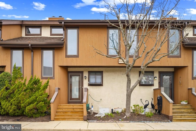 townhome / multi-family property featuring a chimney and stucco siding