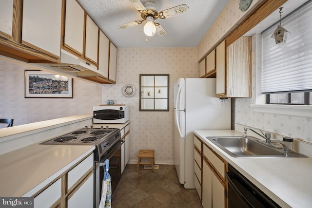 kitchen with light countertops, wallpapered walls, a sink, and white appliances