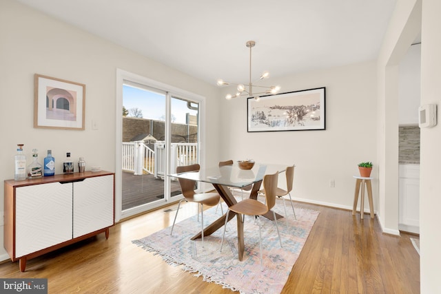 dining area with baseboards, wood finished floors, and a chandelier