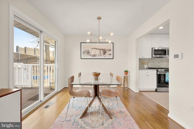 dining space featuring baseboards, light wood-style flooring, a chandelier, and visible vents