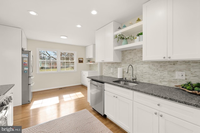 kitchen with open shelves, white cabinets, a sink, dark stone countertops, and stainless steel appliances