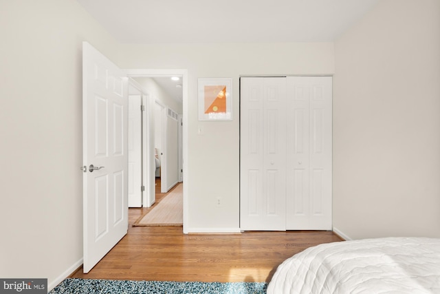 bedroom featuring baseboards, wood finished floors, and a closet