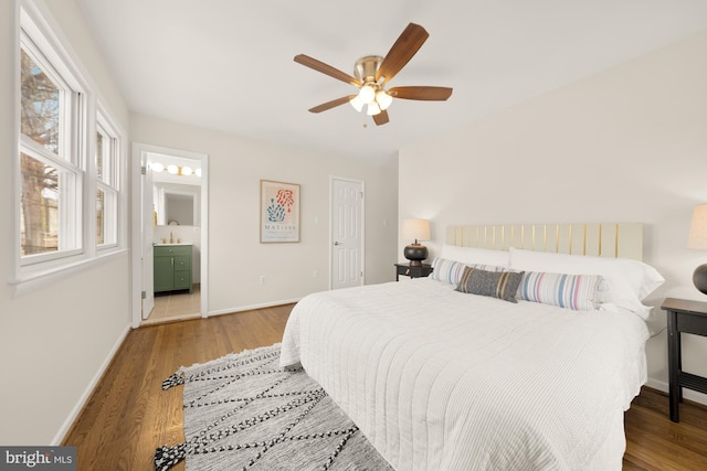 bedroom with baseboards, a ceiling fan, ensuite bath, and wood finished floors
