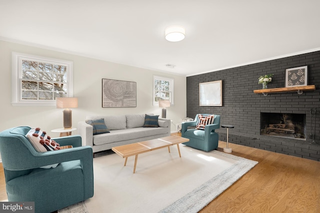 living room featuring brick wall, ornamental molding, a fireplace, and wood finished floors