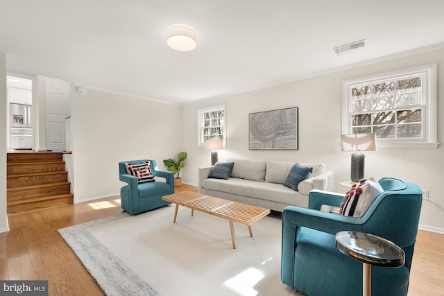 living room featuring baseboards, ornamental molding, wood finished floors, and stairway