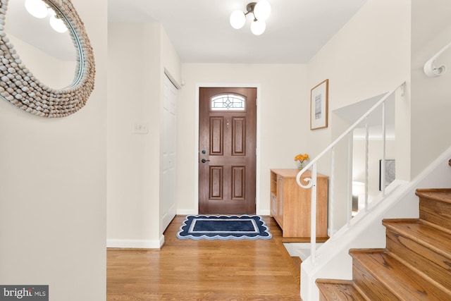 foyer entrance with stairway, baseboards, and wood finished floors