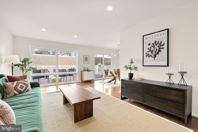 living room with recessed lighting, an inviting chandelier, and wood finished floors