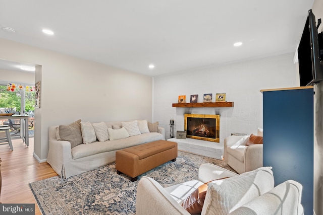 living room featuring light wood-style flooring, recessed lighting, and a glass covered fireplace