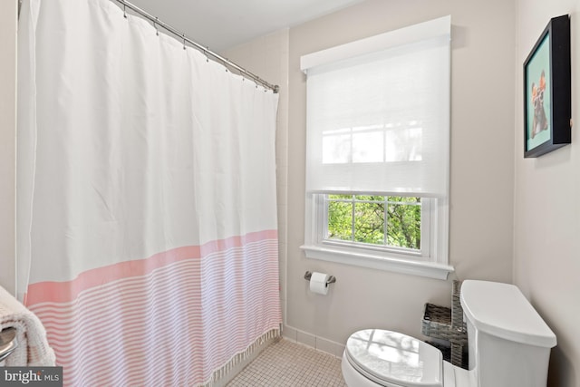 bathroom with toilet, tile patterned flooring, a shower with shower curtain, and baseboards