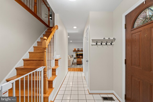 entryway with stairway, light tile patterned floors, a lit fireplace, recessed lighting, and baseboards
