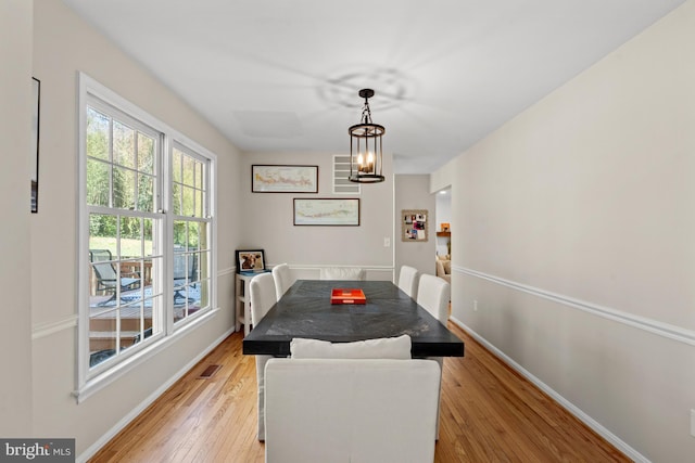 dining room with a chandelier, light wood finished floors, and baseboards