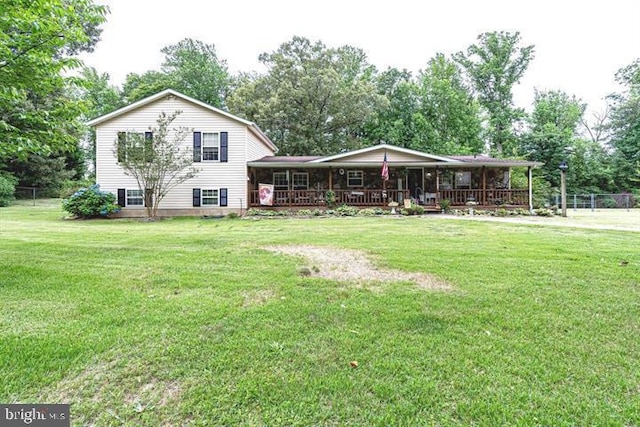 tri-level home featuring a front lawn, covered porch, and fence