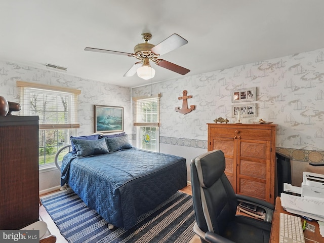 bedroom with wallpapered walls, visible vents, and ceiling fan
