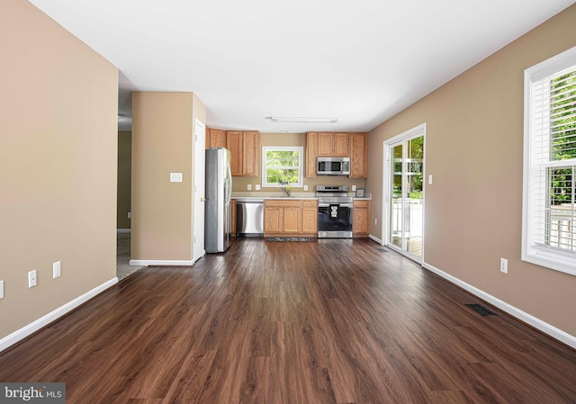 kitchen featuring a healthy amount of sunlight, baseboards, light countertops, dark wood finished floors, and appliances with stainless steel finishes