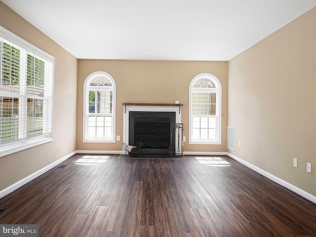 unfurnished living room featuring baseboards, a fireplace with flush hearth, dark wood-style flooring, and visible vents