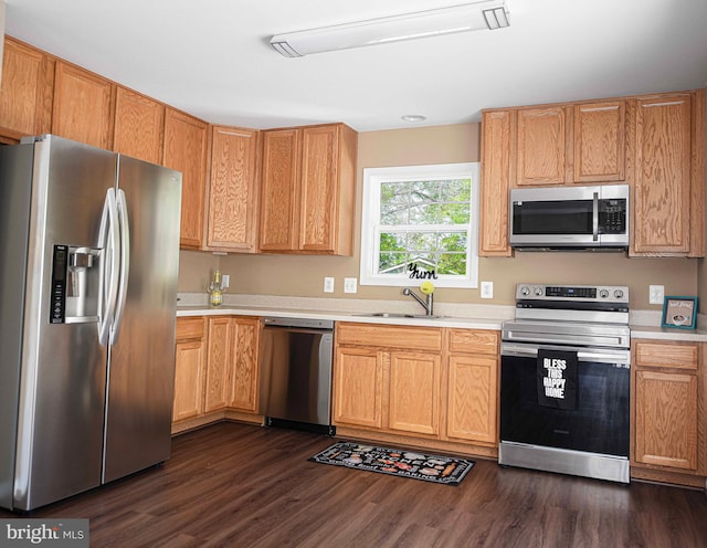 kitchen featuring light countertops, appliances with stainless steel finishes, a sink, and dark wood finished floors
