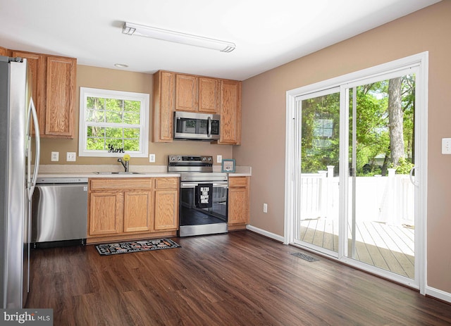 kitchen featuring visible vents, dark wood-style flooring, light countertops, a sink, and stainless steel appliances