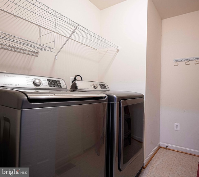 laundry room featuring light tile patterned floors, baseboards, laundry area, and washing machine and clothes dryer