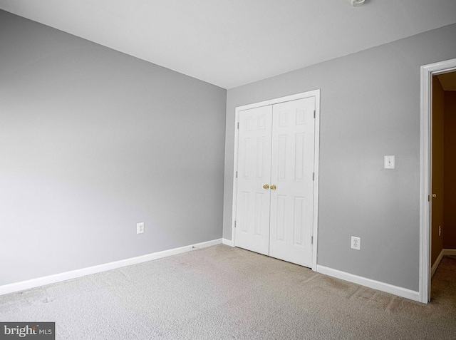 unfurnished bedroom featuring baseboards, carpet floors, and a closet