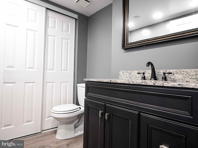 bathroom featuring toilet, visible vents, wood finished floors, and vanity