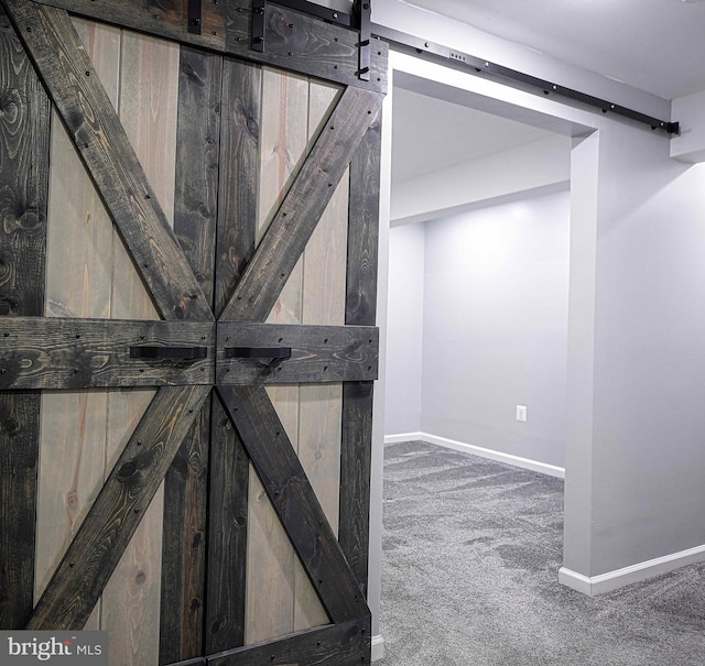 below grade area with carpet flooring, baseboards, and a barn door