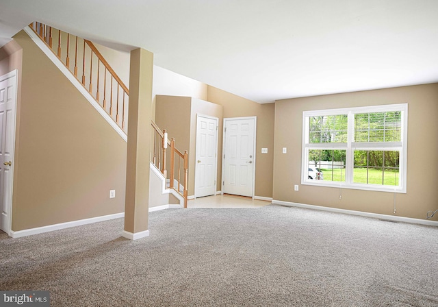unfurnished living room featuring baseboards, stairs, and light colored carpet