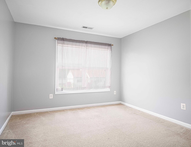 carpeted spare room featuring baseboards and visible vents
