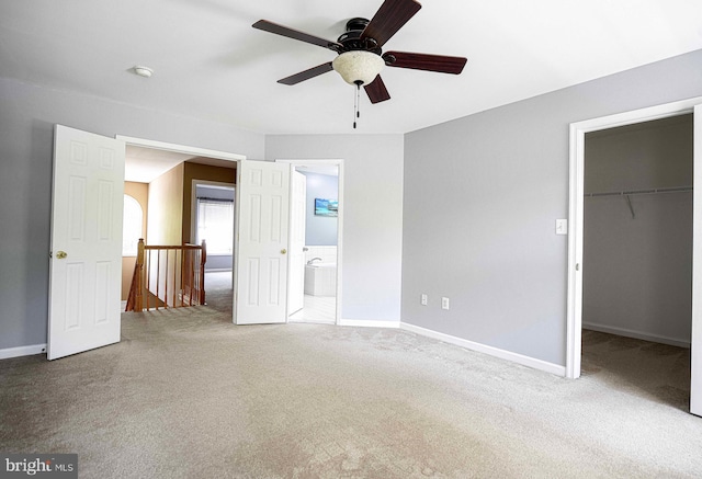unfurnished bedroom featuring carpet floors, baseboards, and a walk in closet