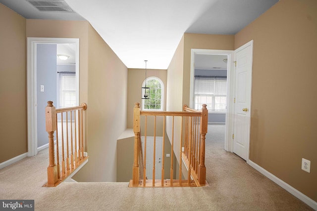 corridor with visible vents, carpet flooring, and an upstairs landing