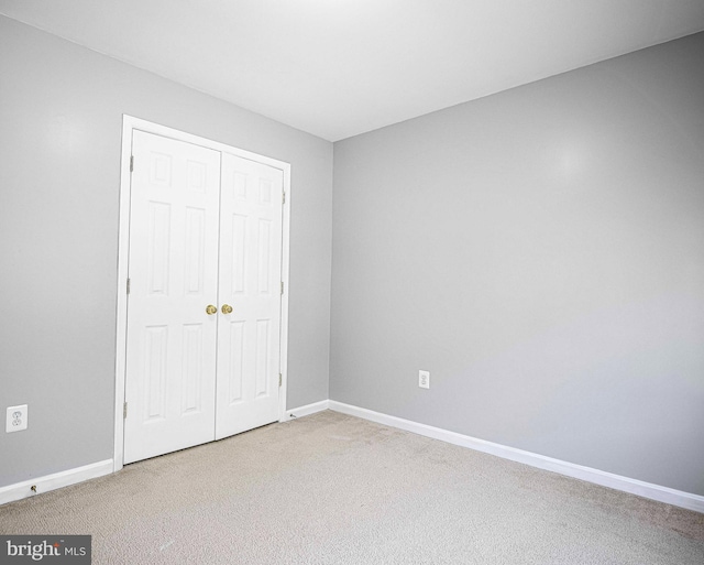 unfurnished bedroom featuring carpet flooring, baseboards, and a closet