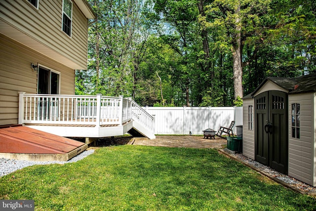 view of yard featuring an outdoor structure, fence, a storage shed, and a deck