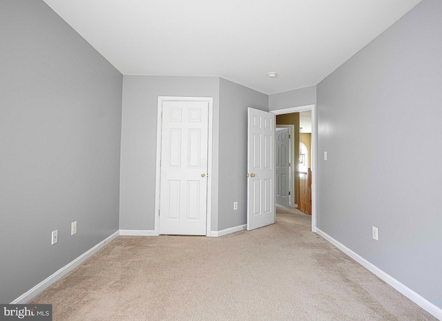 unfurnished bedroom with baseboards and light carpet