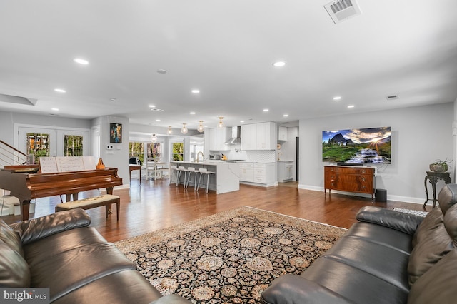 living room with dark wood finished floors, baseboards, visible vents, recessed lighting, and stairs